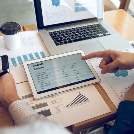 Business partnership coworkers using a tablet to analysis graph company financial budget report and cost work progress and planning for future in office room.